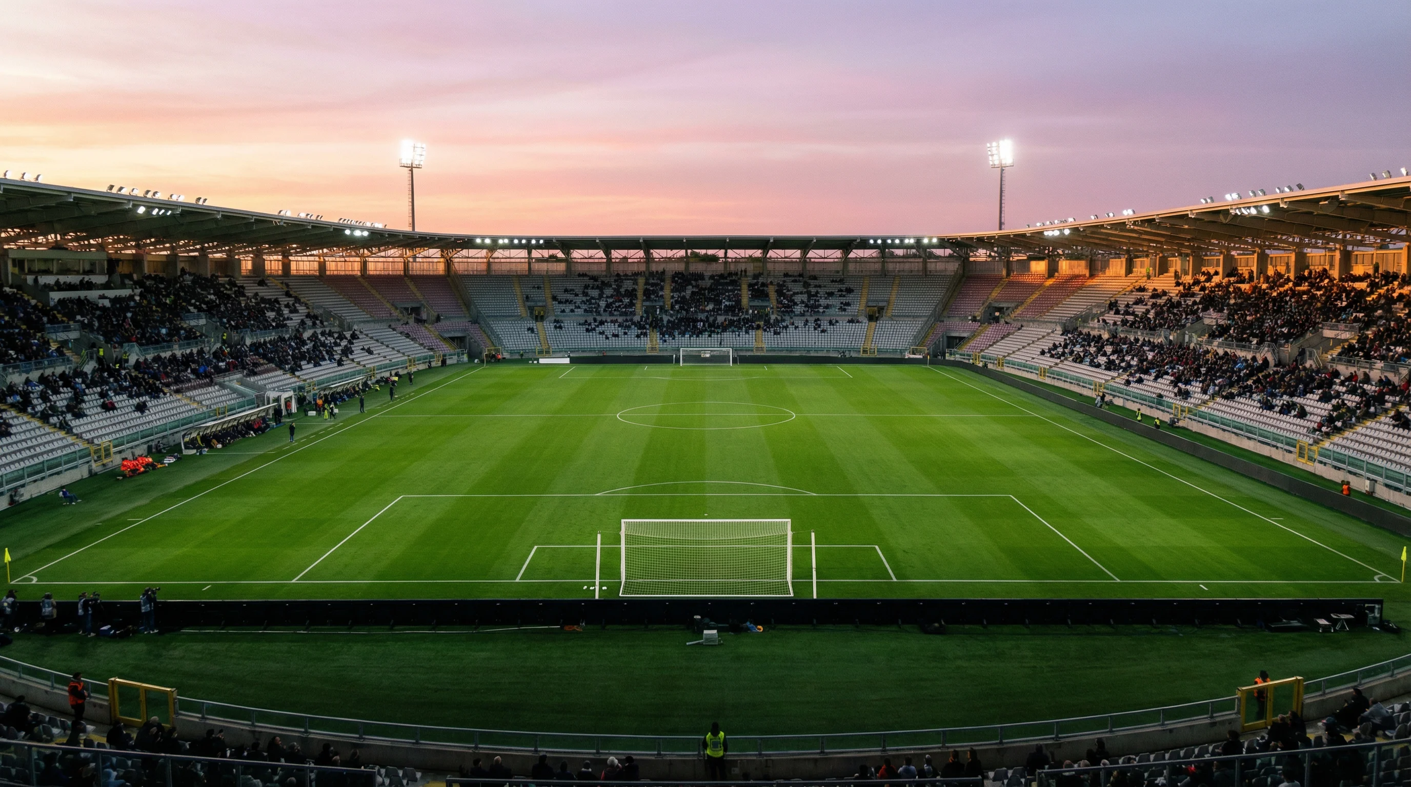 Veduta aerea di uno stadio di calcio italiano con campo verde illuminato al tramonto